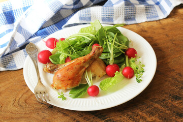 Grilled chicken on a white plate with vegetables on the wooden background.
