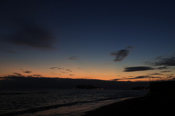 鎌倉・七里ヶ浜海岸から見る江ノ島とオレンジ色になる夕陽とのある風景　夕景