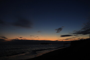 鎌倉・七里ヶ浜海岸から見る江ノ島とオレンジ色になる夕陽とのある風景　夕景