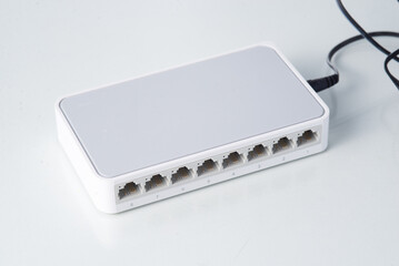 White Ethernet network switch with eight ports on a clean background, used for internet...
