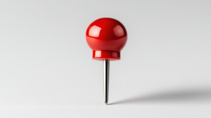 single red push pin stands upright on smooth surface, showcasing its glossy finish and sharp metal point, perfect for pinning notes