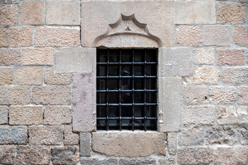 Rectangular window with black cast iron grille on old beige stone wall. From the series Windows of the World.