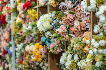 collection of fake plastic flowers rustic pastel color in a flower shop shelf close up bokeh