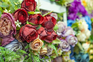 collection of red orange pink  colored rose fake plastic flower close up bokeh