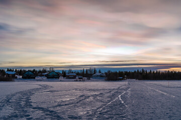 Beautiful winter sunset with rare nacreous clouds known as rainbow clouds over frozen lake Akaslompolo in Finnish Lapland.