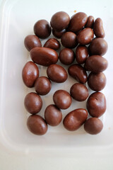 Photo of some dark brown chocolate granules, in plastic container