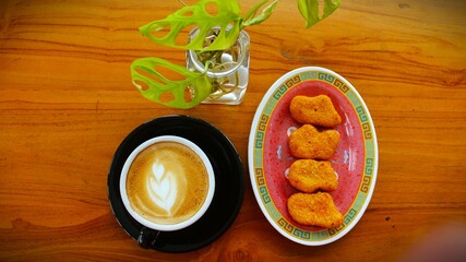 hot coffee latte art and nuggets served on a wooden table