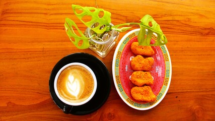 hot coffee latte art and nuggets served on a wooden table