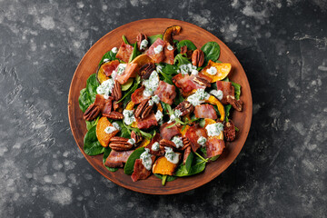 Baked pumpkin bacon salad with spinach and pecan nuts. Healthy food.