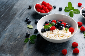 Bowl of cottage cheese, curd cheese with blueberry and raspberry. High protein healthy breakfast or lunch