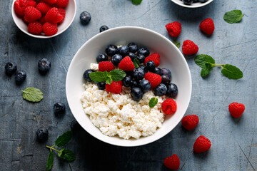 Bowl of cottage cheese, curd cheese with blueberry and raspberry. High protein healthy breakfast or lunch
