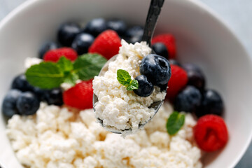 Bowl of cottage cheese, curd cheese with blueberry and raspberry. High protein healthy breakfast or lunch