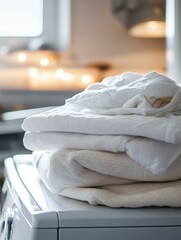 freshly cleaned white clothes folded in perfect layers on washing machine top.