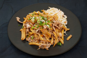 Fast-food dish: fries with gyros meat, sweet and sour sauce and coleslaw stands on the table.