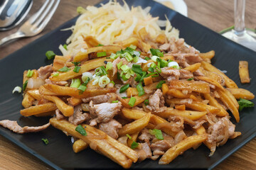 Fast-food dish: fries with gyros meat, sweet and sour sauce and coleslaw stands on the table.