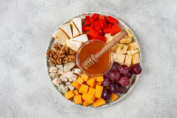 Appetizer, assorted cheese, with nuts and honey, on a round plate, top view, no people,