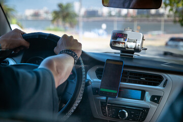Taxi Driver Steering Car with Meter and Smartphone Mounted on Dashboard.