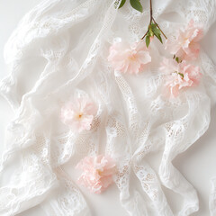 Minimalistic flat lay of white lace fabric and soft pink flowers