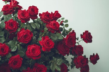 Obraz premium A large and vibrant bouquet of red roses elegantly arranged in a lush, overflowing display, with some stems wrapped in green leaves. The roses vary in bloom size, creating a natural