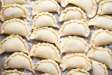 Fresh homemade dumplings prepared on a marble board, showcasing traditional handmade craftsmanship. Raw dough filled with savory ingredients, ready for cooking.
