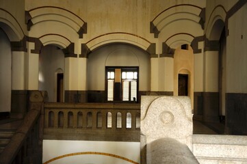 Close-up view of a house with a stair column and wooden balustrade, in the background windows with light in an old house.