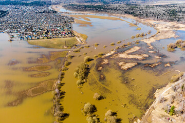 Spring flood on the river with flooded fields in the countryside, aerial view