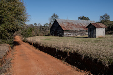 Obraz premium old barn beside a red dirt road in the country