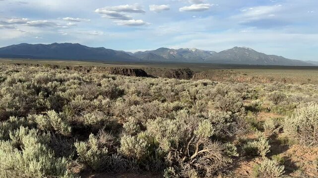 Desert hiking at Rio Grande Gorge Bridge trail near Taos New Mexico, authentic natural hiking canyon, magnificent view of canyon and New mexico mountains, Wheeler peak, desert walking first person