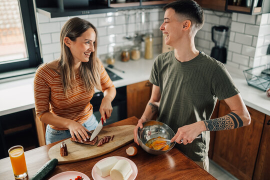 Lesbian couple preparing food and whisking eggs in kitchen - Powered by Adobe