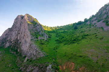 mountain landscape of romania in springtime. green environment. rock formation and grassy hill in morning light. scenery in valisoarei valley. nature tourism