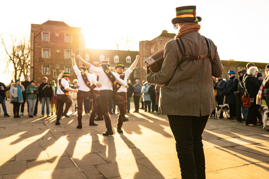 Woman accordion playing seen playing music to a group of traditional English Morris Dancers seen in an English street.