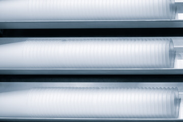 Fototapeta premium Three rows of white plastic cups are stacked on top of each other. The cups are all the same size and shape, and they are all white. The image has a clean and organized look