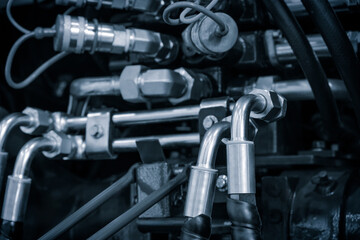 Obraz premium A close-up of a bundle of pipes and wires of an industrial hydraulic machine. The concept is of complexity and technicality, as the various components are intricately connected and interdependent.