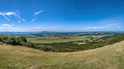 Obraz premium Panoramic View of Rolling Green Hills Under a Blue Sky
