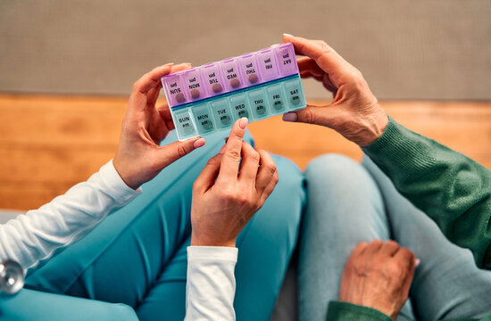 The top view cropped image shows a healthcare worker holding a weekly pill box and showing an elderly patient how to take her medication.