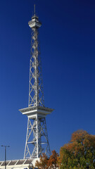 Berliner Funkturm (Berlin Radio Tower) against clear blue sky surrounded by autumn foliage and sunlight