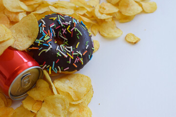 Junk food meal on white background. Red soda or cola can, doughnut, chips. Sweet glazed chocolate...