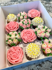 Box of beautiful flower-themed decorated cupcakes