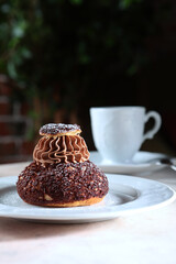 French Shu pastry with peach jam. Custard cake. A cup of coffee. A confectionery product.