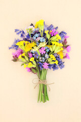 Spring meadow and woodland wildflower posy for birthday or mothers day gift. Springtime Beltane festival floral bouquet seasonal decoration. On cream background.
