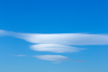 Distinctly shaped lenticular clouds, taking on lens or almond forms, arise as stable, moist air moves over mountains or other obstacles.