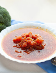 A bowl of hearty tomato soup, garnished with fresh diced tomatoes.  A perfect comforting meal.