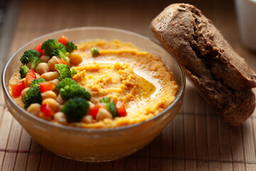 Delicious hummus with chickpeas, broccoli, and red peppers, served with crusty bread.