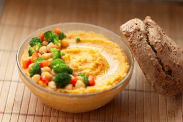 Delicious hummus with chickpeas, broccoli, and bell peppers, served with a side of whole-wheat bread.