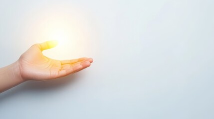 Fototapeta premium Illuminated light bulb held in hand, a symbol of innovation and creative inspiration against white backdrop