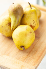 Ripe yellow pears on a wooden cutting board, ready for cooking or eating.