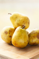 Ripe, yellow pears on a wooden cutting board.  A close-up shot showcasing the texture and color of the fruit.