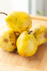 Ripe yellow pears on a wooden surface.  A close-up shot of four pears, showcasing their texture and color.