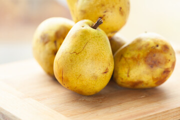 Ripe yellow pears on a wooden surface.  A close-up shot showcasing the texture and color of the fruit.