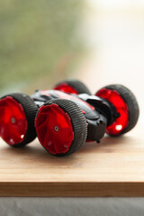 Red and black toy car with large wheels on a wooden surface.